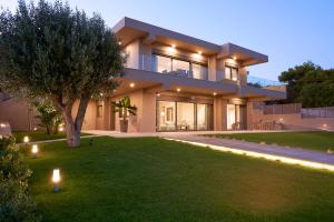 ein großes Haus mit Licht auf dem Rasen in der Unterkunft Elaia Luxury Suites Lagonisi in Lagonisi