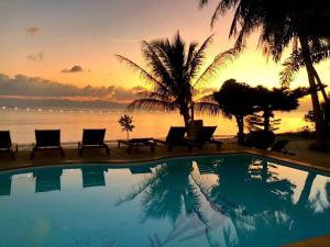 a resort swimming pool with a sunset in the background at Phangan Lodge in Baan Tai