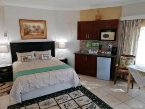 a bedroom with a large bed and a kitchen at Fairbairn Guest Farm in Maclear