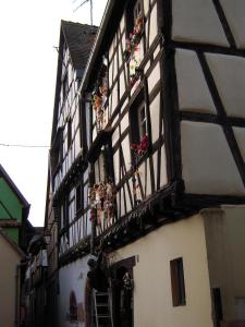 un bâtiment avec des poupées sur son côté dans l'établissement La Maison Vigneronne, à Riquewihr