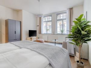1 dormitorio con cama blanca y maceta en limehome Leipzig Oelßner's Hof, en Leipzig