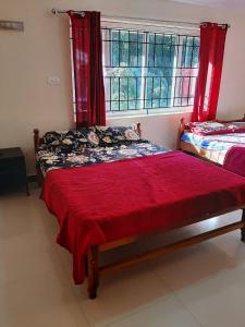 a bedroom with two beds with red curtains and a window at jack N jill holidays inn in Ooty