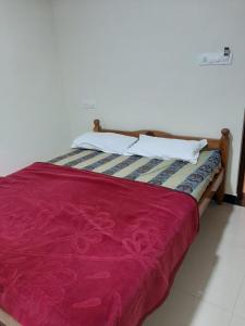 a bed with a red blanket and white pillows at jack N jill holidays inn in Ooty