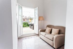 ein Wohnzimmer mit einem Sofa und einem offenen Fenster in der Unterkunft Hotel Boutique Elvira Plaza in Sevilla