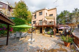 ein Haus mit einer Terrasse mit Stühlen und einem Sonnenschirm in der Unterkunft Pinecone Platres - 3 Units in Platres