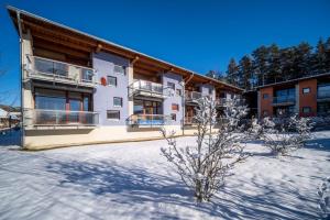 a building with snow in front of it at Apartment Doky D8 - Lipno Home in Lipno nad Vltavou