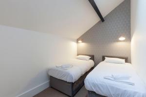 two beds in a small room with white sheets at The 'Tailors' Apartment in Leicester