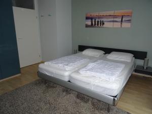 ein Bett mit weißer Bettwäsche in einem Schlafzimmer in der Unterkunft Kustverhuur, Appartement aan Zee, Prachtig appartement op de begane grond PS 13-001 in Breskens