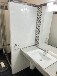 a white bathroom with a sink and a mirror at Aqua Wellness Apartments in Hajdúszoboszló