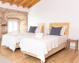 due letti in una stanza con pareti bianche e pavimenti in legno di A BURGUESA - GUESTHOUSE a Castelo de Vide
