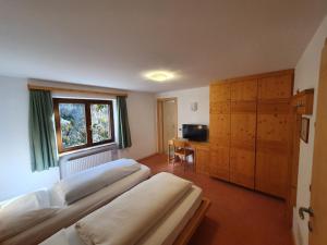 a bedroom with three beds and a desk and a window at ALBERGO BAR RISTORANTE DOLOMIA in Badia