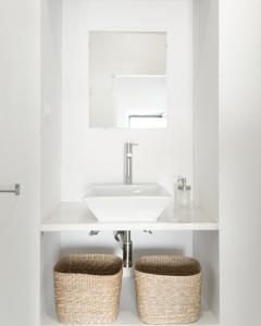 a bathroom with a sink and two wicker stools at A BURGUESA - GUESTHOUSE in Castelo de Vide