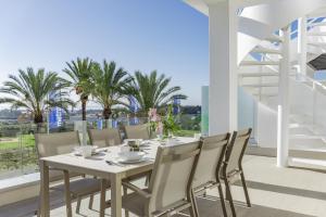 uma mesa branca e cadeiras numa varanda com palmeiras em LM12A- Brand new apartment in a quiet location em Estepona