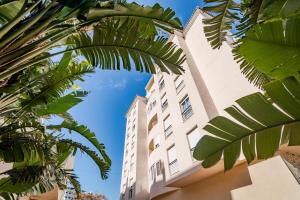 ein hohes Gebäude mit Palmen davor in der Unterkunft PDM- Lovely apartment with stunning views Estepona in Estepona