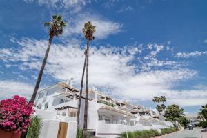 two palm trees in front of a white building at IVY-Modern 3 bedroom apt private garden in Marbella
