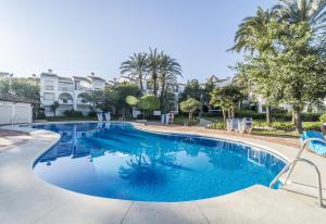 una piscina en un complejo con sillas y palmeras en HB Comfortable Beachfront Holiday Apartment, en Estepona