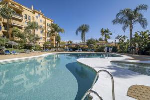 a swimming pool at a resort with palm trees at LA-Beautiful 3 bedroom Penthouse close to sea in Marbella