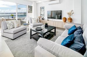 uma sala de estar com um sofá e cadeiras e uma televisão em CP - Front line beach Playa del Cristo em Estepona