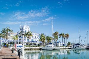 a marina with boats and a building with a clock tower at CP - Modern Beachside Apartment in Estepona in Estepona