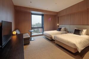 Habitación de hotel con 2 camas y TV de pantalla plana. en Yokohama Tokyu REI Hotel, en Yokohama