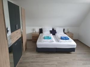 ein Schlafzimmer mit einem Bett mit weißen Laken und blauen Kissen in der Unterkunft Ferienhaus Trudi in Winterberg
