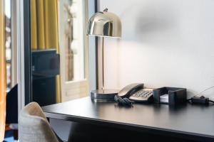 a desk with a phone and a lamp on it at ProfilHotels Copenhagen Plaza in Copenhagen