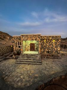 a stone building with a door and some stairs at Sab Bani Khamis House in Sa‘ab Banī Khamīs