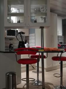 a kitchen with two red bar stools and a counter at A home away from home in Nelspruit