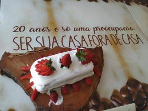 a cake with strawberries and whipped cream on it at Café Palace Hotel in Três Pontas