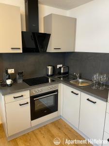 a kitchen with white cabinets and a stove and a sink at Appartment Höflehner - Sommercard in Großsölk