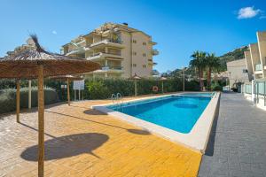 a swimming pool with an umbrella next to a building at Casa Vistamar in Altea