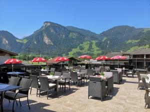 ein Restaurant mit Tischen und Stühlen mit Bergen im Hintergrund in der Unterkunft Hotel Theresia in Ramsau im Zillertal