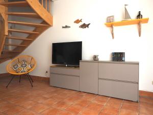 ein Wohnzimmer mit einem Flachbild-TV und einem Stuhl in der Unterkunft Ferienhaus Segelbär in Hooksiel
