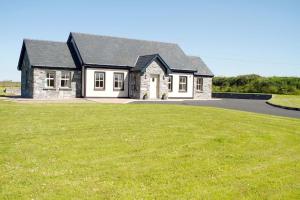 een huis met een groot grasveld ervoor bij Cahermaclanchy House B&B in Doolin