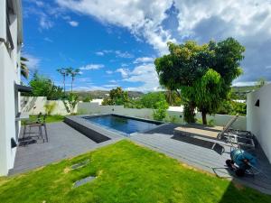 a backyard with a swimming pool and a lawn at Villa Pluton - Meublé de tourisme 4 étoiles in Saint-Gilles les Bains