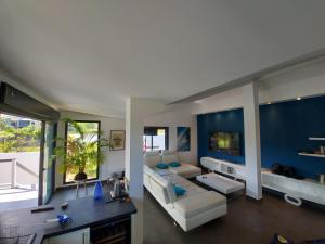 a large living room with a white couch and blue walls at Villa Pluton - Meublé de tourisme 4 étoiles in Saint-Gilles les Bains