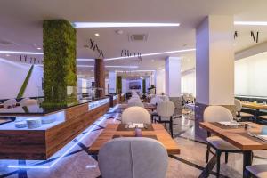 un restaurante con mesas, sillas y plantas en Hotel Colombo, en Lido di Jesolo