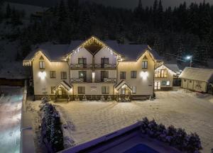 a large house in the snow at night at Villa Shale MarSo in Bukovel
