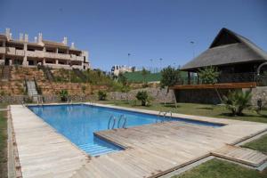 una piscina con terraza de madera junto a un edificio en HL 005 2 Bedroom Apartment,HDA golf resort, Murcia, en Murcia