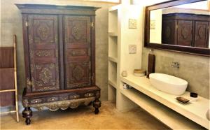 a bathroom with a sink and a large wooden cabinet at The Spice House Mirissa in Mirissa
