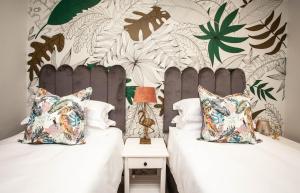 a bedroom with two beds and a wall with plants at The view 42 in Jeffreys Bay