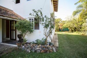 a garden with a tree and rocks in front of a house at Caiowa Floripa guesthouse in Florianópolis