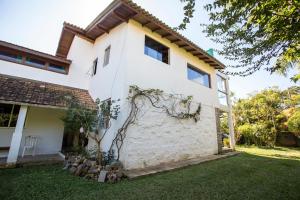 a white house with a tree in the yard at Caiowa Floripa guesthouse in Florianópolis