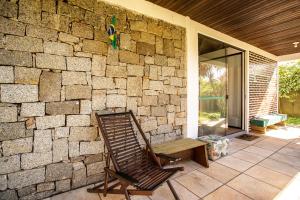 a rocking chair sitting next to a stone wall at Caiowa Floripa guesthouse in Florianópolis