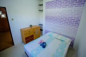 a small room with a bed and a brick wall at Caiowa Floripa guesthouse in Florianópolis