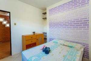 a bedroom with a bed with a purple brick wall at Caiowa Floripa guesthouse in Florianópolis