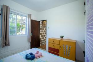 a bedroom with a bed and a dresser and a window at Caiowa Floripa guesthouse in Florianópolis