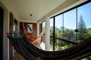 a hammock in a room with large windows at Caiowa Floripa guesthouse in Florianópolis