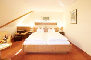 a bedroom with a large bed with white sheets at Wander- & Wellnesshotel Nägele in Höchenschwand +24 photos