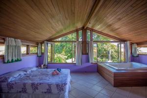 a bedroom with a bed and a bath tub and windows at Caiowa Floripa guesthouse in Florianópolis